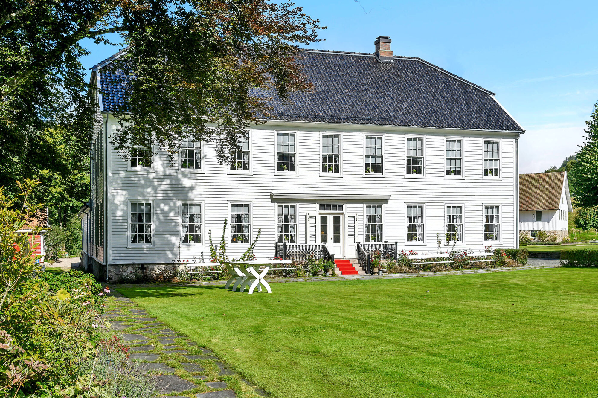 Fasaden til Boen gård med stor gressplen foran.