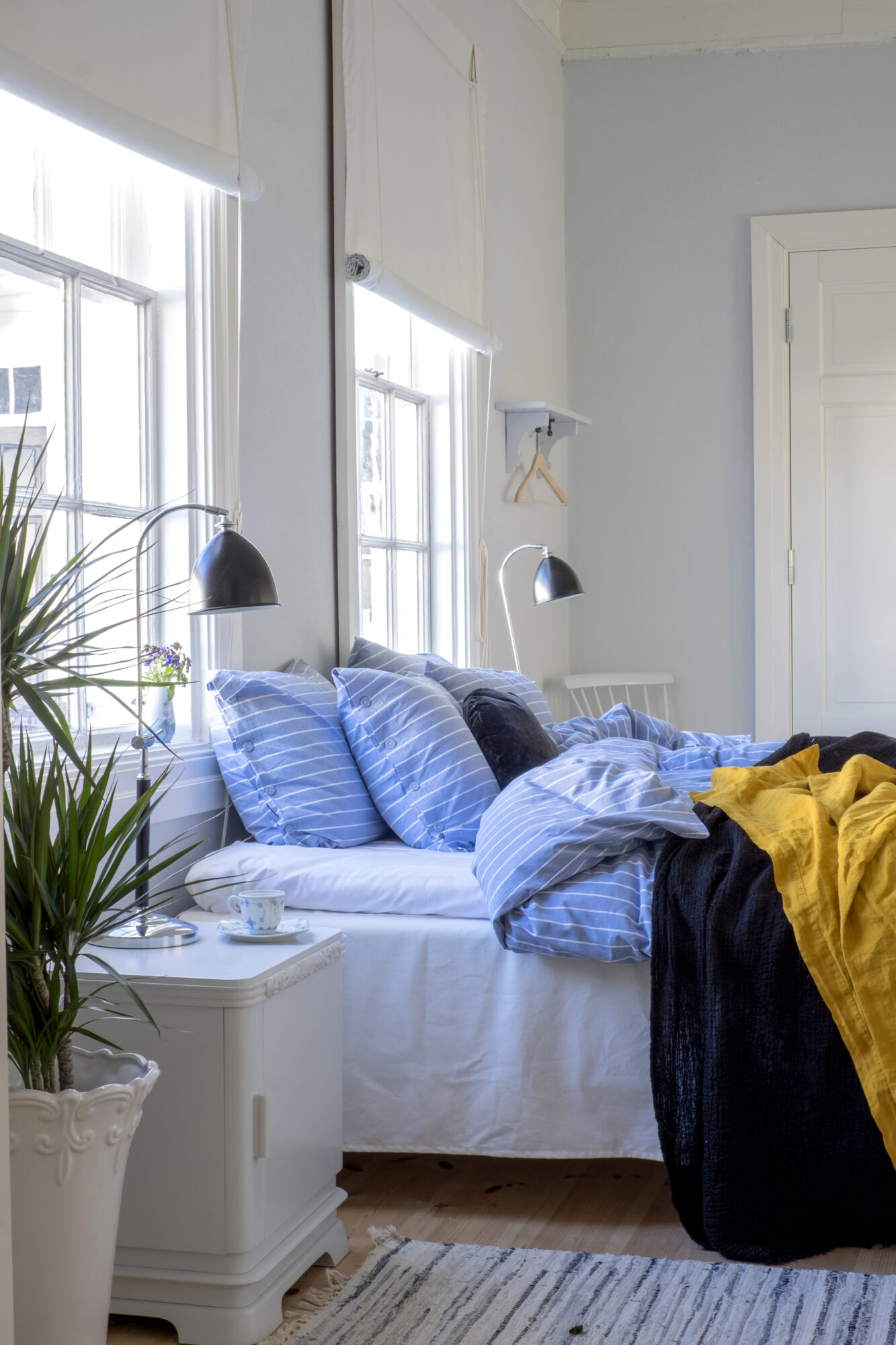 Soverom med lys innredning og stripete sengetøy.